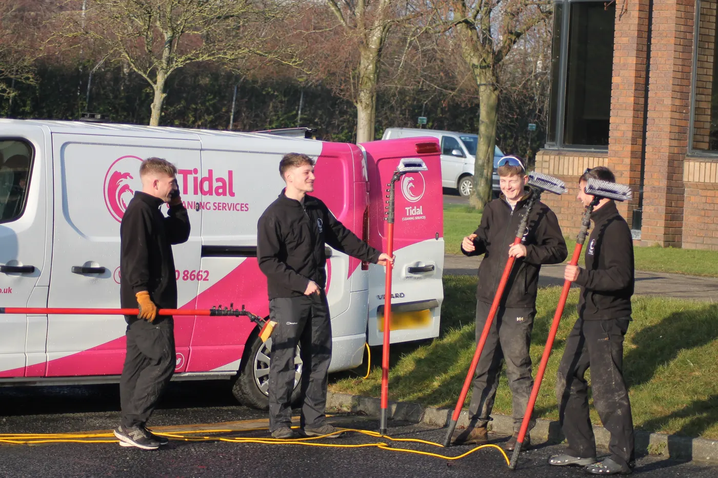 Tidal window cleaners with water-fed poles beside a branded Tidal van